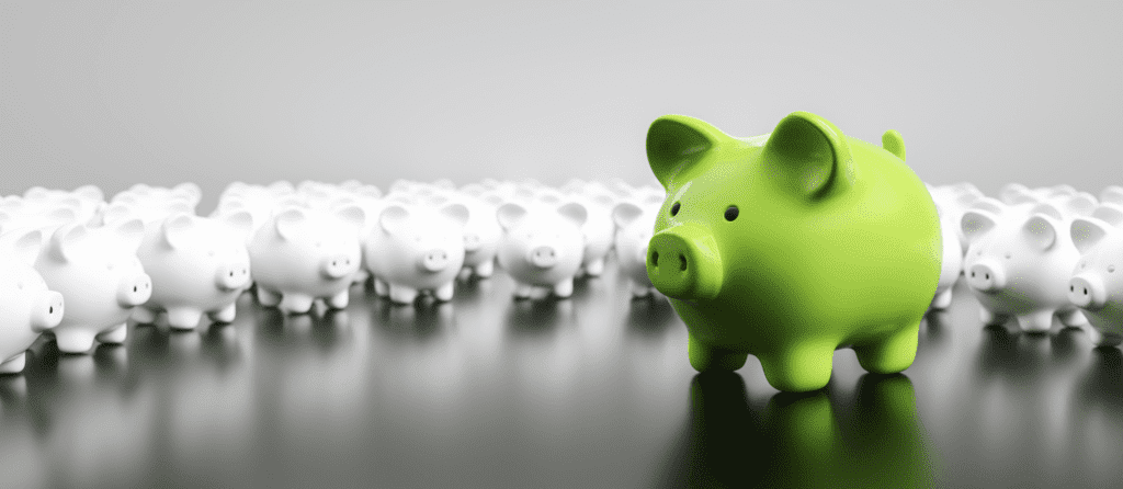 Big Green Piggy Bank with Many Small White Piggy Banks on a Table 